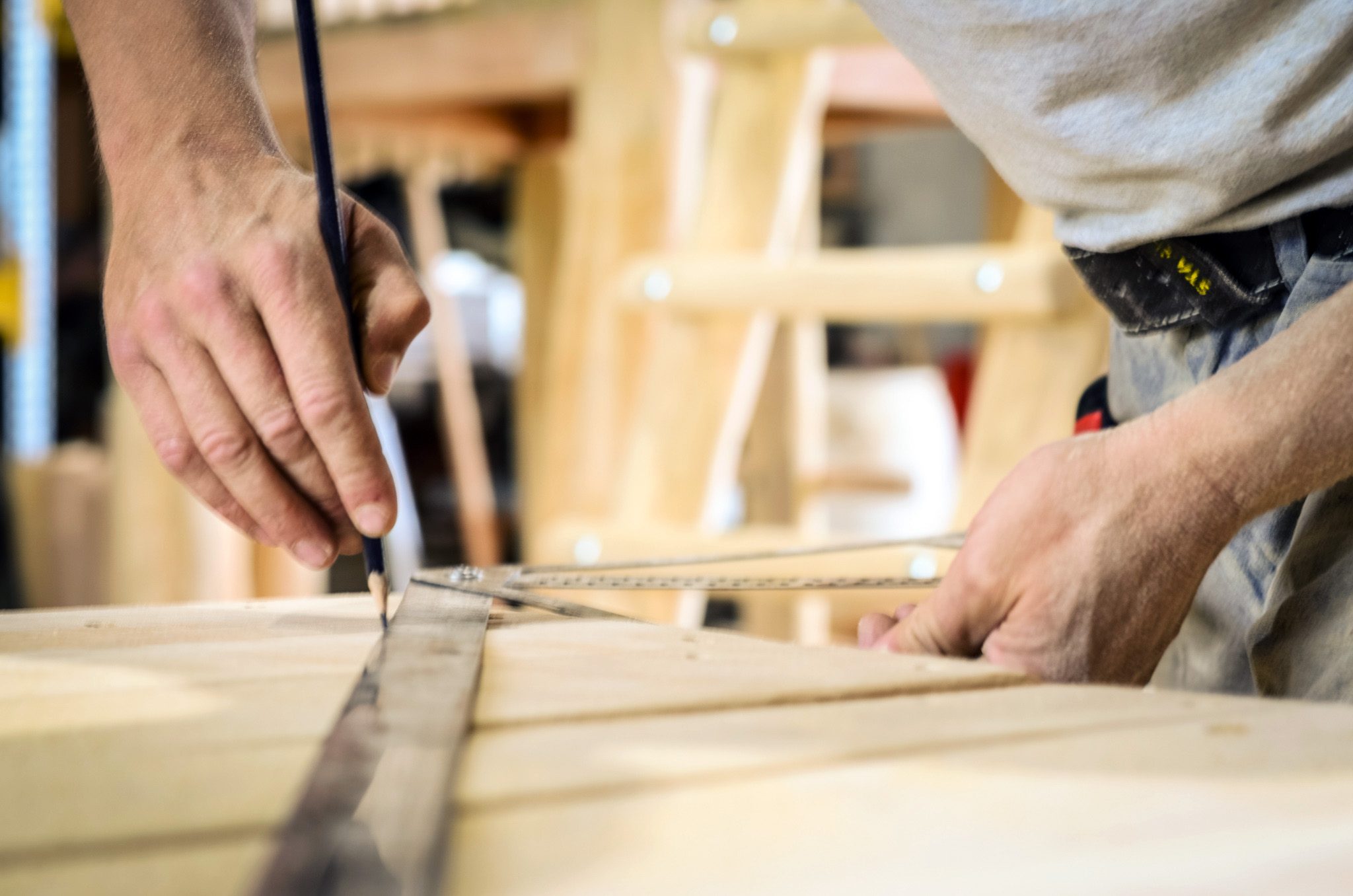 Zimmerer zeichnet Maße auf einem Holzbauteil an